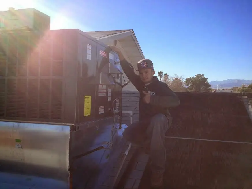 HVAC technician performing Air Duct Cleaning on a rooftop unit in Oakfield